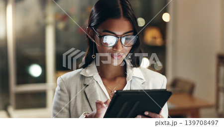 Tablet, reflection and woman in office with glasses, overtime with planning and scroll on social media. Vision, research and businesswoman typing email, late at night work on future ideas for agency. Tablet, reflection and woman in office with glasses, overtime with planning and scroll on social media. Vision, research and businesswoman typing email, late at night work on future ideas for agency. 139708497