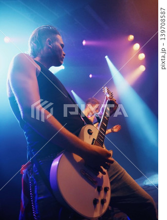 Music, guitar and lighting with man on stage for concert, show or performance at festival from below. Party, event or entertainment and musician or guitarist playing instrument at musical production Music, guitar and lighting with man on stage for concert, show or performance at festival from below. Party, event or entertainment and musician or guitarist playing instrument at musical production 139708587