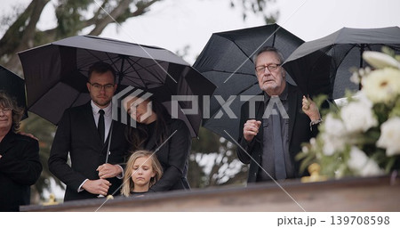 Death, funeral and umbrella, people at coffin for service in graveyard in respect, mourning and support. Flowers, rain and loss, family at casket in cemetery with memory, grief and grave for burial. Death, funeral and umbrella, people at coffin for service in graveyard in respect, mourning and support. Flowers, rain and loss, family at casket in cemetery with memory, grief and grave for burial. 139708598