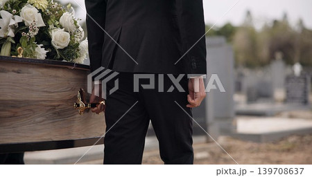 Coffin, hands and man walking at funeral ceremony outdoor with pallbearers at tomb. Death, grief and person carrying casket at cemetery, graveyard or family service of people mourning at windy event 139708637