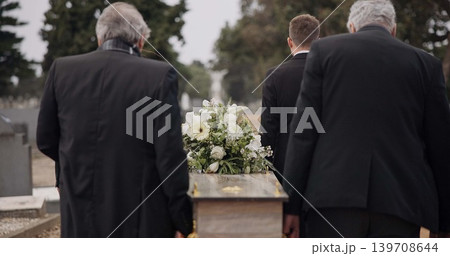 Men, coffin and pallbearers walking at cemetery ceremony outdoor at burial tomb. Death, grief and group casket at funeral, carry to graveyard and family service of people mourning at windy event. 139708644