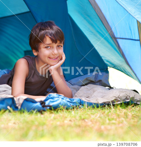 Boy, child and camping, relax in tent and summer vacation with travel and happy in portrait outdoor. Rest on sleeping bag, young camper with smile and adventure in nature, childhood and recreation Boy, child and camping, relax in tent and summer vacation with travel and happy in portrait outdoor. Rest on sleeping bag, young camper with smile and adventure in nature, childhood and recreation 139708706