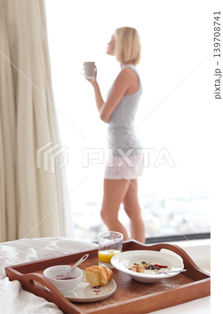 Young woman, view and breakfast in bedroom to relax, morning routine and health with coffee for wellness. Person, cappucino or blonde hair nutrition for fruit detox, calm or healthy food in apartment 139708741