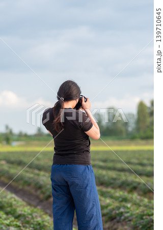 Woman taking photos in agricultural field during daylight capturing nature landscape outdoor lifestyle moments Woman taking photos in agricultural field during daylight capturing nature landscape outdoor lifestyle moments 139710645