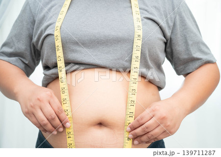 Asian woman with fat belly big size overweight and obesity with measure tape. Asian woman with fat belly big size overweight and obesity with measure tape. 139711287