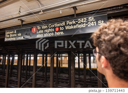 New york, usa august 18,2024. Commuter studying nyc subway sign for uptown and the bronx on the broadway local platform, waiting on the station platform New york, usa august 18,2024. Commuter studying nyc subway sign for uptown and the bronx on the broadway local platform, waiting on the station platform 139711443