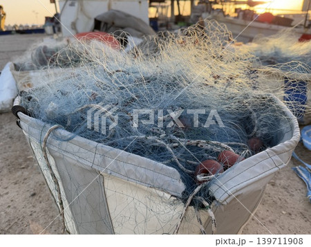 Fishing nets piled in a container at a harbor near the sea during sunset 139711908