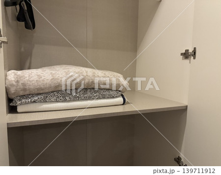 Empty closet interior with folded linens in neutral tones, ideal for organization or storage concept Empty closet interior with folded linens in neutral tones, ideal for organization or storage concept 139711912