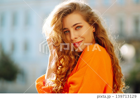 Female tourist in bright dress enjoys sights of the city on sunny day. Concept of lifestyle, fashion Female tourist in bright dress enjoys sights of the city on sunny day. Concept of lifestyle, fashion 139713129