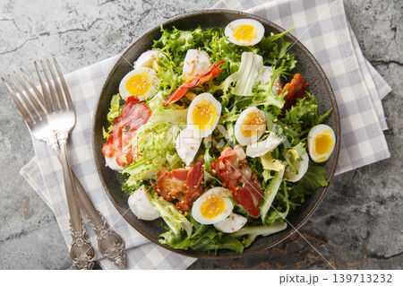 healthy low-carb salad of soft-boiled quail eggs, bacon, mozzarella, sesame seeds and mixed greens close-up in a plate. Horizontal top view 139713232