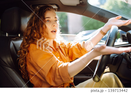 Emotional woman drives a car. The concept of fast movement, traveling by car. Emotional woman drives a car. The concept of fast movement, traveling by car. 139713442