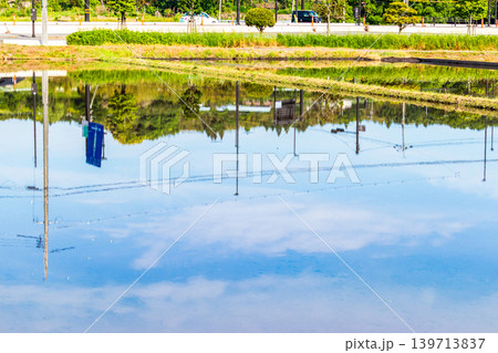 水を張った田植え前の水田に映り込んだ田舎の風景 水を張った田植え前の水田に映り込んだ田舎の風景 139713837