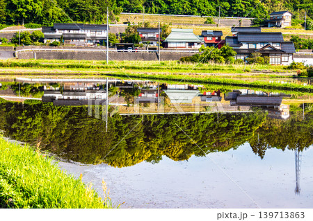水を張った田植え前の水田に映り込んだ田舎の風景 139713863