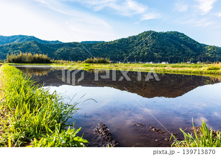 水を張った田植え前の水田に映り込んだ田舎の風景 水を張った田植え前の水田に映り込んだ田舎の風景 139713870