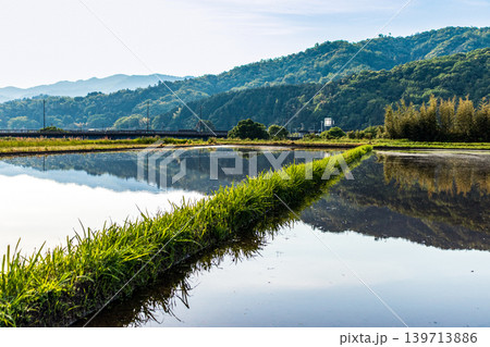 水を張った田植え前の水田に映り込んだ田舎の風景 水を張った田植え前の水田に映り込んだ田舎の風景 139713886