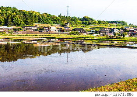 水を張った田植え前の水田に映り込んだ田舎の風景 水を張った田植え前の水田に映り込んだ田舎の風景 139713896