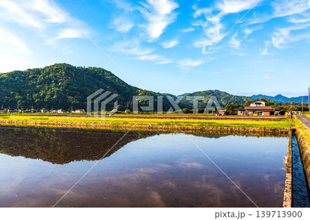 水を張った田植え前の水田に映り込んだ田舎の風景 水を張った田植え前の水田に映り込んだ田舎の風景 139713900