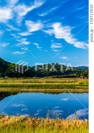 水を張った田植え前の水田に映り込んだ田舎の風景 水を張った田植え前の水田に映り込んだ田舎の風景 139713910