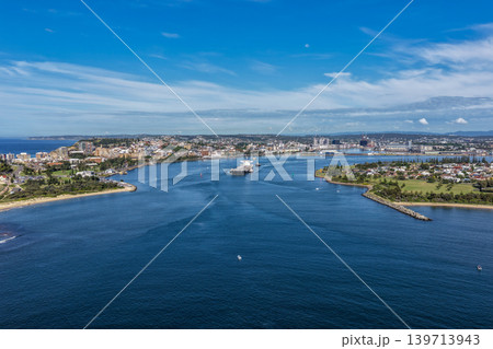 Aerial drone view of a large cargo ship being escorted by tug boats through Newcastle Harbour in New South Wales, Australia. Aerial drone view of a large cargo ship being escorted by tug boats through Newcastle Harbour in New South Wales, Australia. 139713943