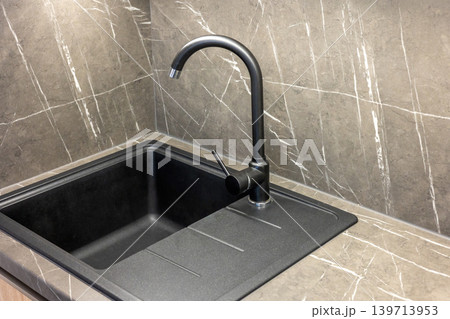 Top view of a sink with a modern black faucet. Top view of a sink with a modern black faucet. 139713953