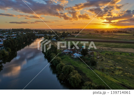 Aerial view of sunset over Morpeth River and bridge in New South Wales, Australia. Scenic landscape showing warm evening light reflecting across water and structure spanning river. Aerial view of sunset over Morpeth River and bridge in New South Wales, Australia. Scenic landscape showing warm evening light reflecting across water and structure spanning river. 139714061