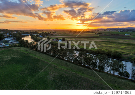 Aerial view of sunset over Morpeth River and bridge in New South Wales, Australia. Scenic landscape showing warm evening light reflecting across water and structure spanning river. Aerial view of sunset over Morpeth River and bridge in New South Wales, Australia. Scenic landscape showing warm evening light reflecting across water and structure spanning river. 139714062