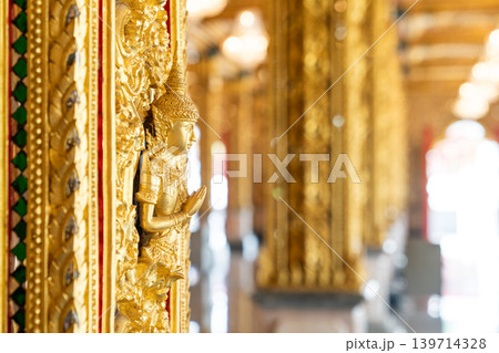 Mythical protector figures across temple wall gilded high relief gold surfaces mirrored details carved borders Thai sacred design reverence grandeur. 139714328