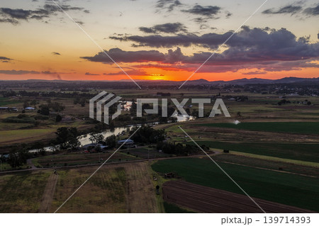 Aerial view of colourful sunset over Morpeth River and surrounding farmland in New South Wales, Australia. Scenic rural landscape showing vibrant sky colours reflecting across water and agricultural Aerial view of colourful sunset over Morpeth River and surrounding farmland in New South Wales, Australia. Scenic rural landscape showing vibrant sky colours reflecting across water and agricultural 139714393