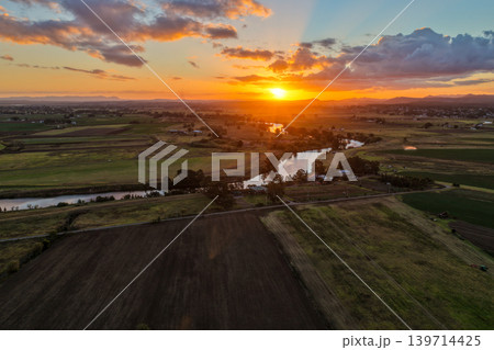 Aerial view of colourful sunset over Morpeth River and surrounding farmland in New South Wales, Australia. Scenic rural landscape showing vibrant sky colours reflecting across water and agricultural Aerial view of colourful sunset over Morpeth River and surrounding farmland in New South Wales, Australia. Scenic rural landscape showing vibrant sky colours reflecting across water and agricultural 139714425