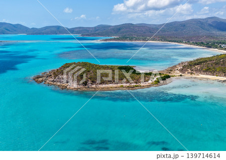 Aerial view over Hydeaway Bay in QLD Australia. Drone photograph captures the tropical coastline, clear ocean water and scenic waterfront landscape from above. Aerial view over Hydeaway Bay in QLD Australia. Drone photograph captures the tropical coastline, clear ocean water and scenic waterfront landscape from above. 139714614