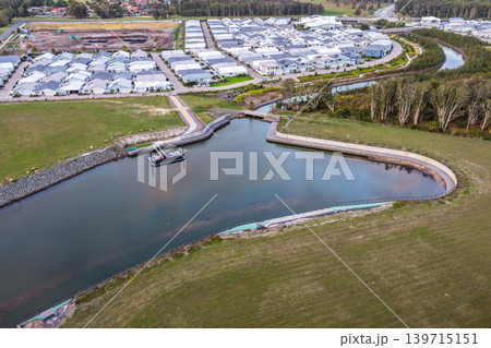 Aerial drone view looking down over a jetty extending into a calm water inlet leading into Pipers Bay in Forster, New South Wales, Australia. 139715151