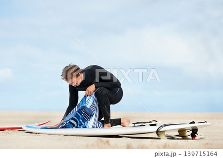 Surfer, man and getting ready with surfboard in nature with wetsuit, blue sky or preparing with mock up space. Extreme sports, athlete and person outdoor for training, surfing workout or watersports Surfer, man and getting ready with surfboard in nature with wetsuit, blue sky or preparing with mock up space. Extreme sports, athlete and person outdoor for training, surfing workout or watersports 139715164
