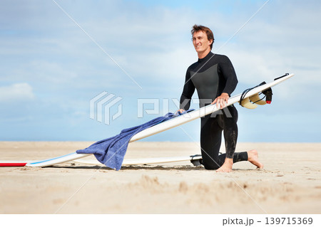 Surfer, man and getting ready with surfboard by ocean with wetsuit, blue sky and dressing with mock up space. Extreme sports, athlete and person on beach for training, surfing workout and towel Surfer, man and getting ready with surfboard by ocean with wetsuit, blue sky and dressing with mock up space. Extreme sports, athlete and person on beach for training, surfing workout and towel 139715369