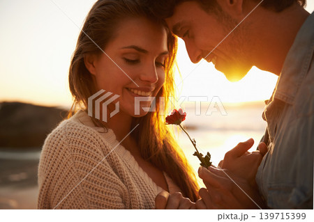 Flower, sunset and young couple at beach on vacation, adventure or holiday for valentines day. Love, smile and man and woman with floral plant by ocean for tropical weekend trip on romantic date. Flower, sunset and young couple at beach on vacation, adventure or holiday for valentines day. Love, smile and man and woman with floral plant by ocean for tropical weekend trip on romantic date. 139715399