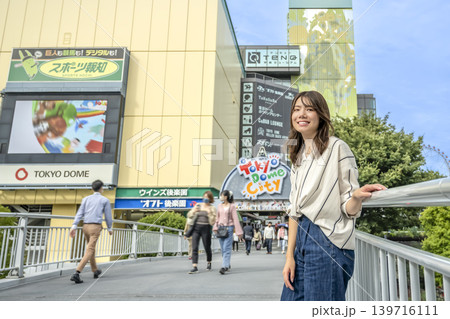 水道橋駅前の歩道橋で案内する笑顔の若い女性 139716111