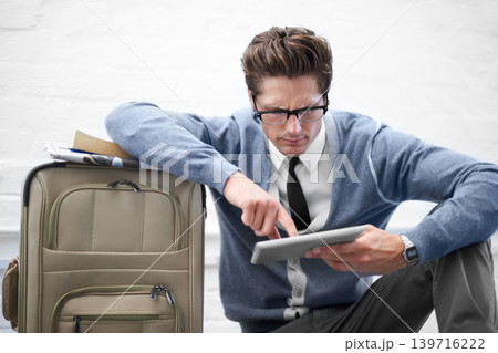 Business man, reading or baggage with tablet, floor and stress with app, flight or travel by wall background. Entrepreneur, person or touchscreen on social media, bag or check booking for immigration 139716222