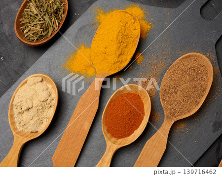 Assorted ground spices in wooden spoons, turmeric, paprika, nutmeg, ginger, dark stone surface Assorted ground spices in wooden spoons, turmeric, paprika, nutmeg, ginger, dark stone surface 139716462