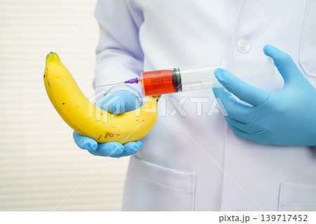 Male doctor making an injection to a banana with a syringe, penis health. Male doctor making an injection to a banana with a syringe, penis health. 139717452