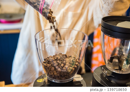 カフェでの作業中　コーヒーミルにコーヒー豆を注ぎ入れる。 139718650