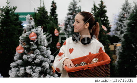A store sells Christmas decorations. A young girl is choosing decorations for the Christmas celebration. A store sells Christmas decorations. A young girl is choosing decorations for the Christmas celebration. 139719339
