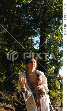 A beautiful brunette dressed in boho style meditates and dances in the forest. A magical ritual takes place against a green forest backdrop. 139719393
