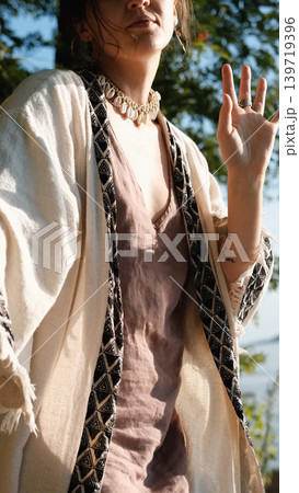A beautiful brunette dressed in boho style meditates and dances in the forest. A magical ritual takes place against a green forest backdrop. A beautiful brunette dressed in boho style meditates and dances in the forest. A magical ritual takes place against a green forest backdrop. 139719396