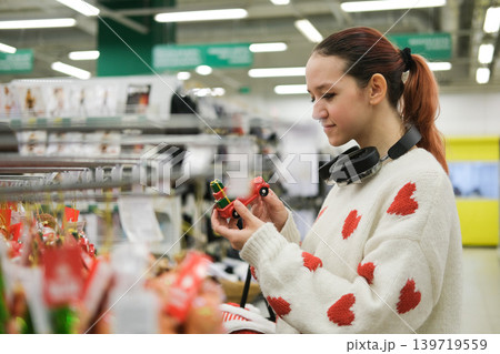 A store sells Christmas decorations. A young girl is choosing decorations for the Christmas celebration. A store sells Christmas decorations. A young girl is choosing decorations for the Christmas celebration. 139719559