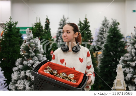 A store sells Christmas decorations. A young girl is choosing decorations for the Christmas celebration. A store sells Christmas decorations. A young girl is choosing decorations for the Christmas celebration. 139719569