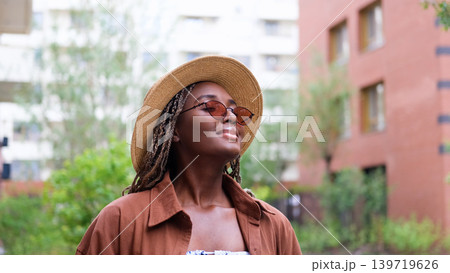 Young woman resting and relaxing while walking on city street in new eco-friendly residential complex. Relaxation and stress-free concept. Young woman resting and relaxing while walking on city street in new eco-friendly residential complex. Relaxation and stress-free concept. 139719626