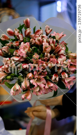Female florist arranges delicate bouquet of pink alstroemeria flowers. Flower delivery. Small business concept Female florist arranges delicate bouquet of pink alstroemeria flowers. Flower delivery. Small business concept 139719736