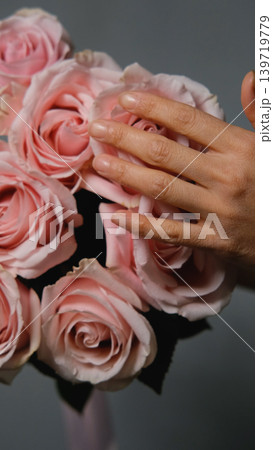 A florist creates a custom bouquet. Close-up of a bouquet of roses against a gray background. Beautiful pink roses at a flower shop. A florist creates a custom bouquet. Close-up of a bouquet of roses against a gray background. Beautiful pink roses at a flower shop. 139719779