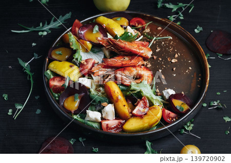 Colorful roasted peach and beet salad with arugula and feta on rustic plate 139720902
