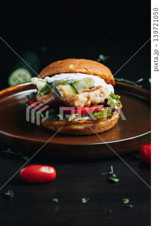 Tasty fish burger with fresh vegetables on dark wooden surface Tasty fish burger with fresh vegetables on dark wooden surface 139721050
