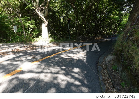 新緑の山道に降り注ぐ木漏れ日と舗装路の風景 新緑の山道に降り注ぐ木漏れ日と舗装路の風景 139722745